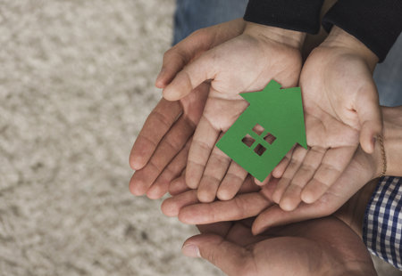 Group Of Hands Holding A Green Cut Out Of House In Their Palms Summary Image