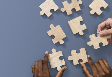 Wooden puzzle pieces with hands holding some of the pieces 